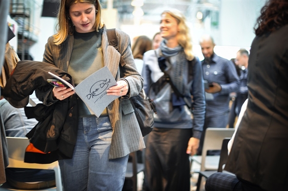 A participant of the DenimDeal EndEvent walks through the room while reading the booklet.