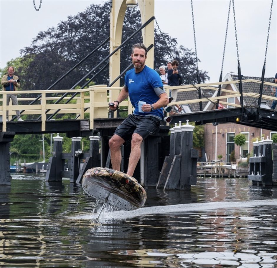 Merijn Tinga supt voor een brug langs, met een wegwerpbekertje in zijn hand.