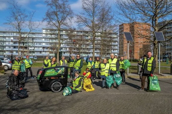 De Straatjutters samen op de foto, in hun gele hesjes met groene afvalzakken in de hand.
