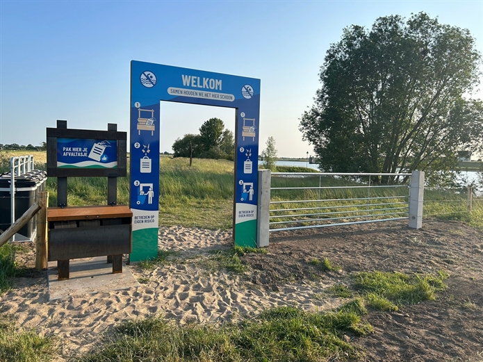 Een speciale tekst op de entreepoort nodigt de bezoeker van het rivierstrand uit om een afvaltasje mee te pakken.