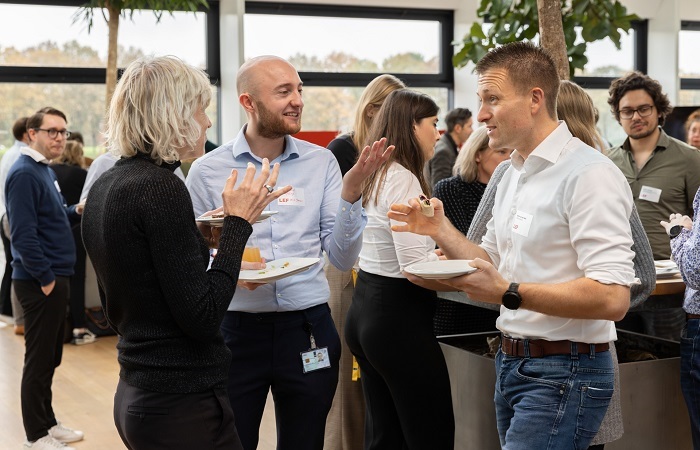 Mensen lunchen staande en zijn in gesprek met elkaar