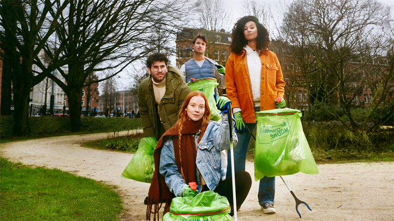 4 volwassenen in een park met grijpstokken en afvalzakken.